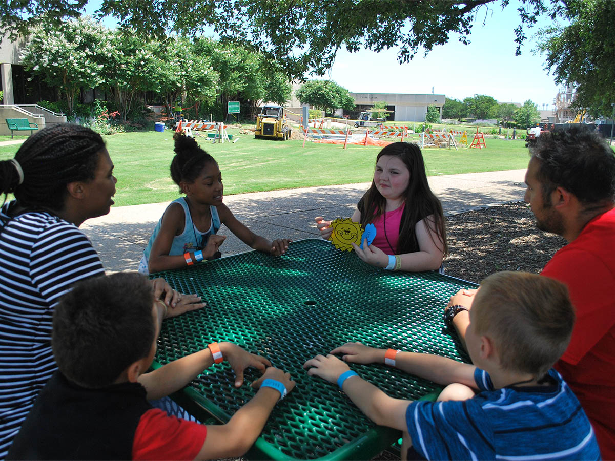Brighter Days counselor leading an outdoor group activity with children at a community site in Dallas TX